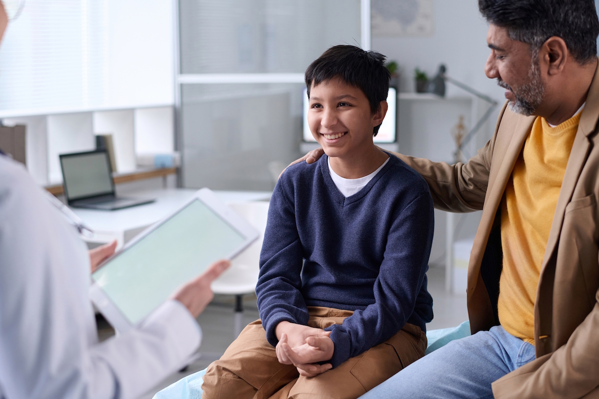 fall sports hand injury smiling boy visiting doctor with dad